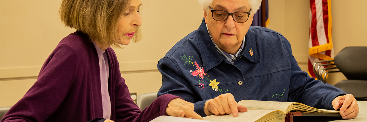 Two Women looking into old book during genealogy class