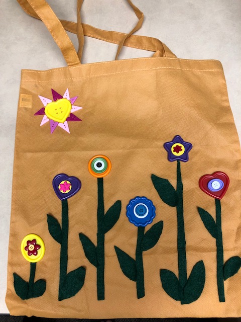 Tote bag decorated with craft materials creating six flowers and a sun