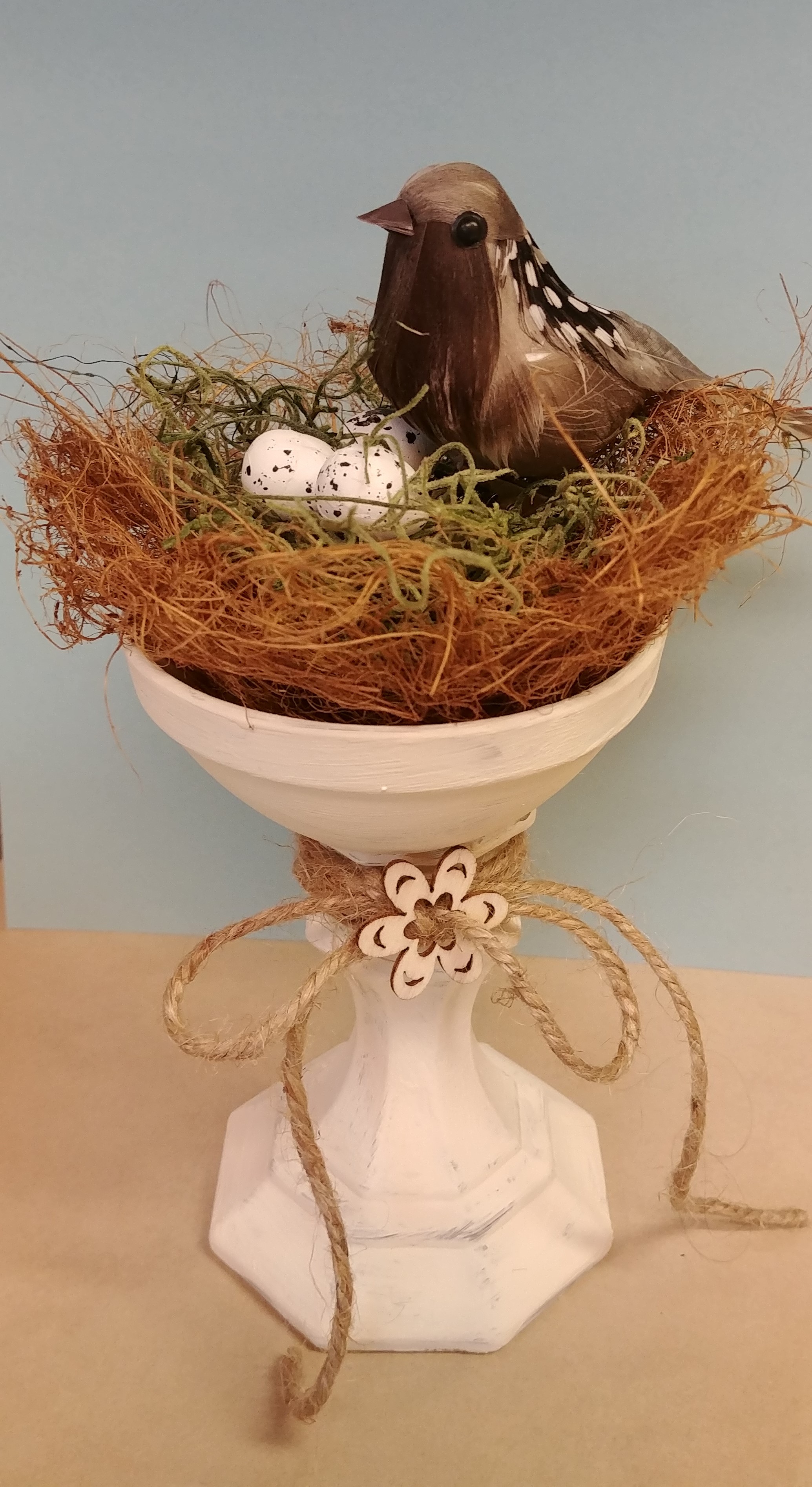 faux bird in a nest on a holder