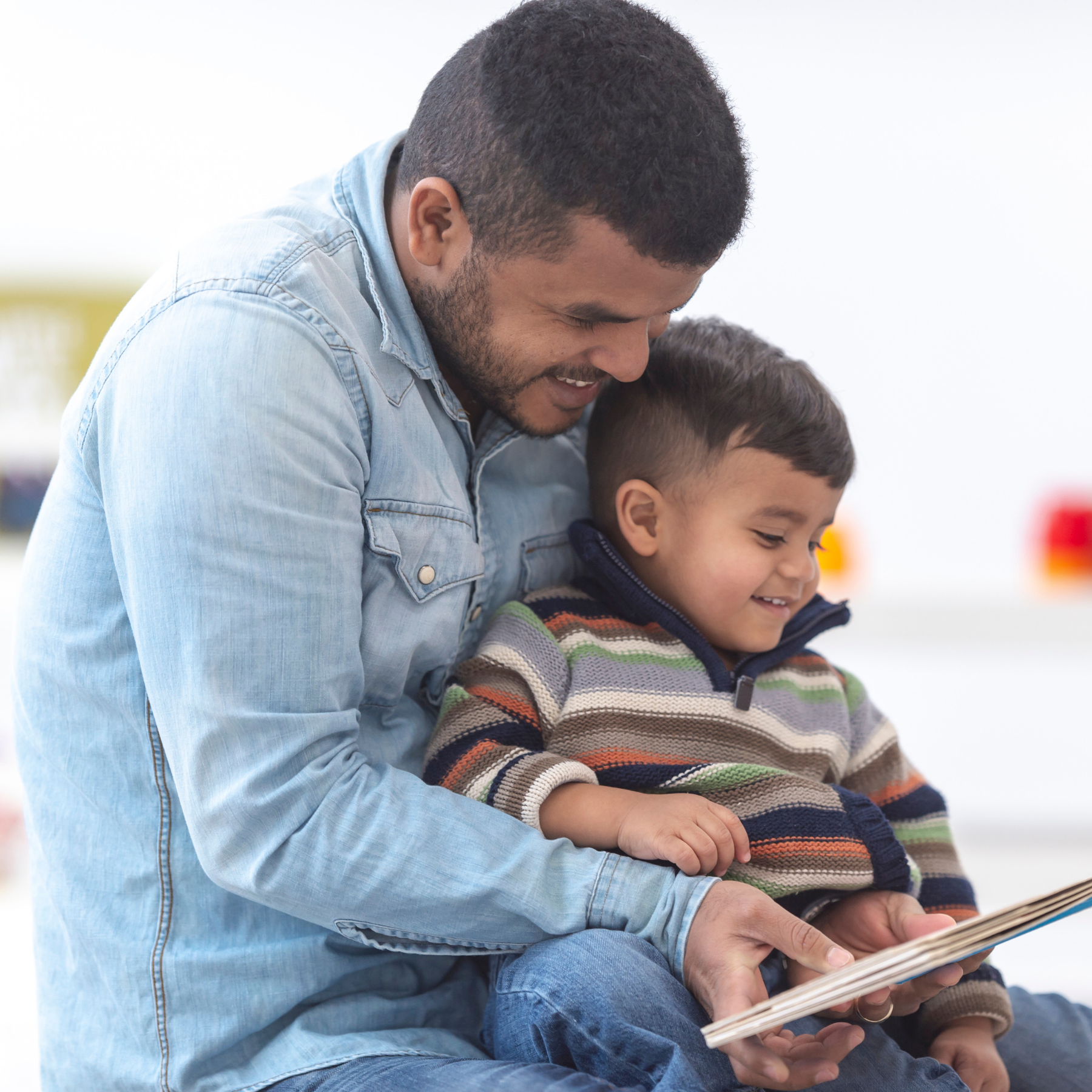 father reading to son sitting in his lap