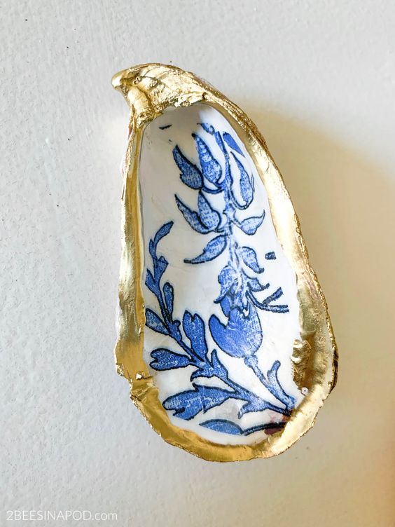 Decoupage oyster shell with blue and white motif and golden rim.