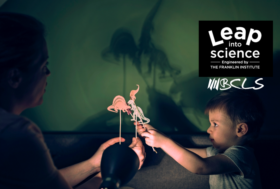 parent and child playing with dinosaur-shaped shadow puppets