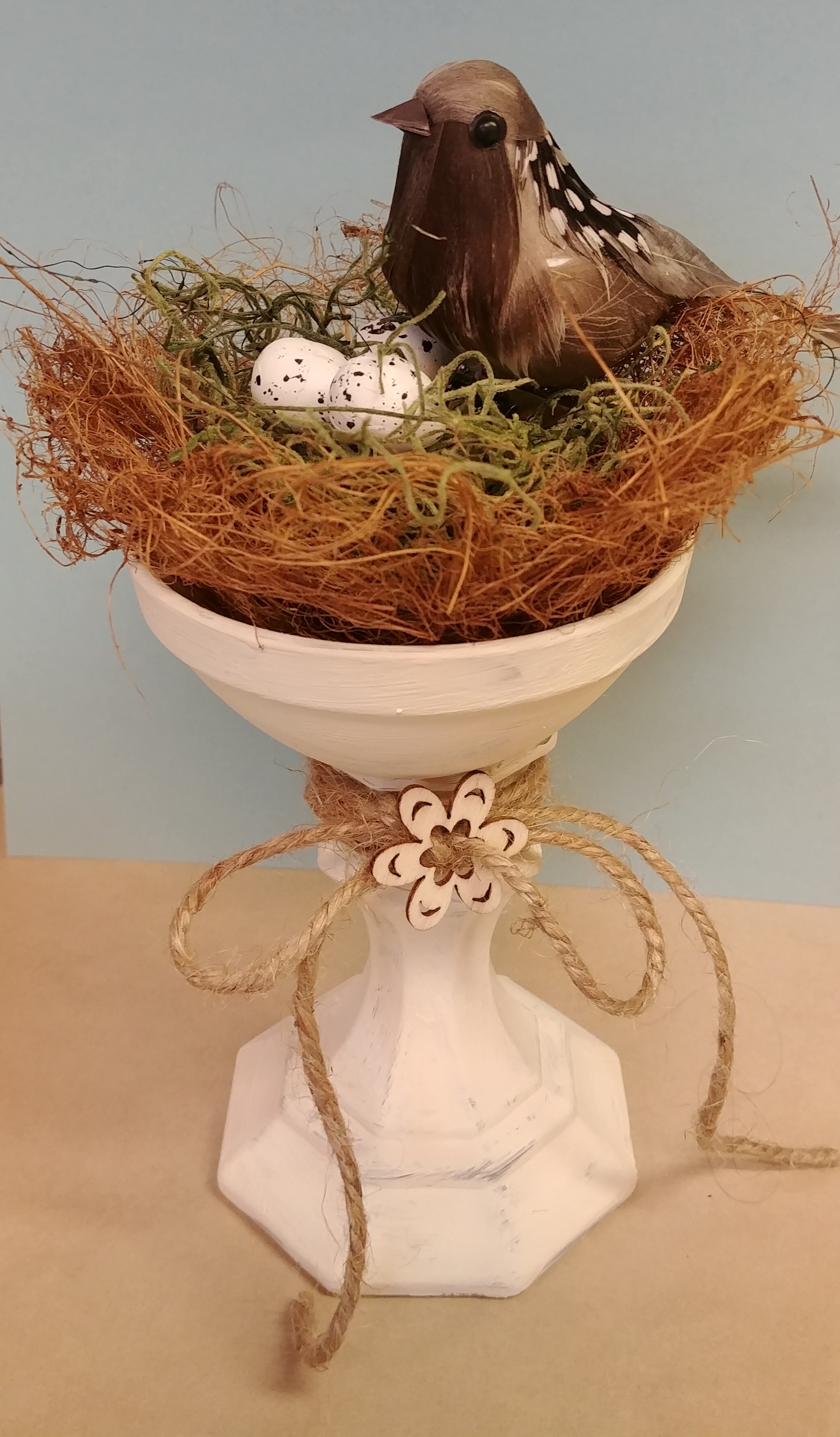 bird on nest with eggs nestled in a candlestick holder