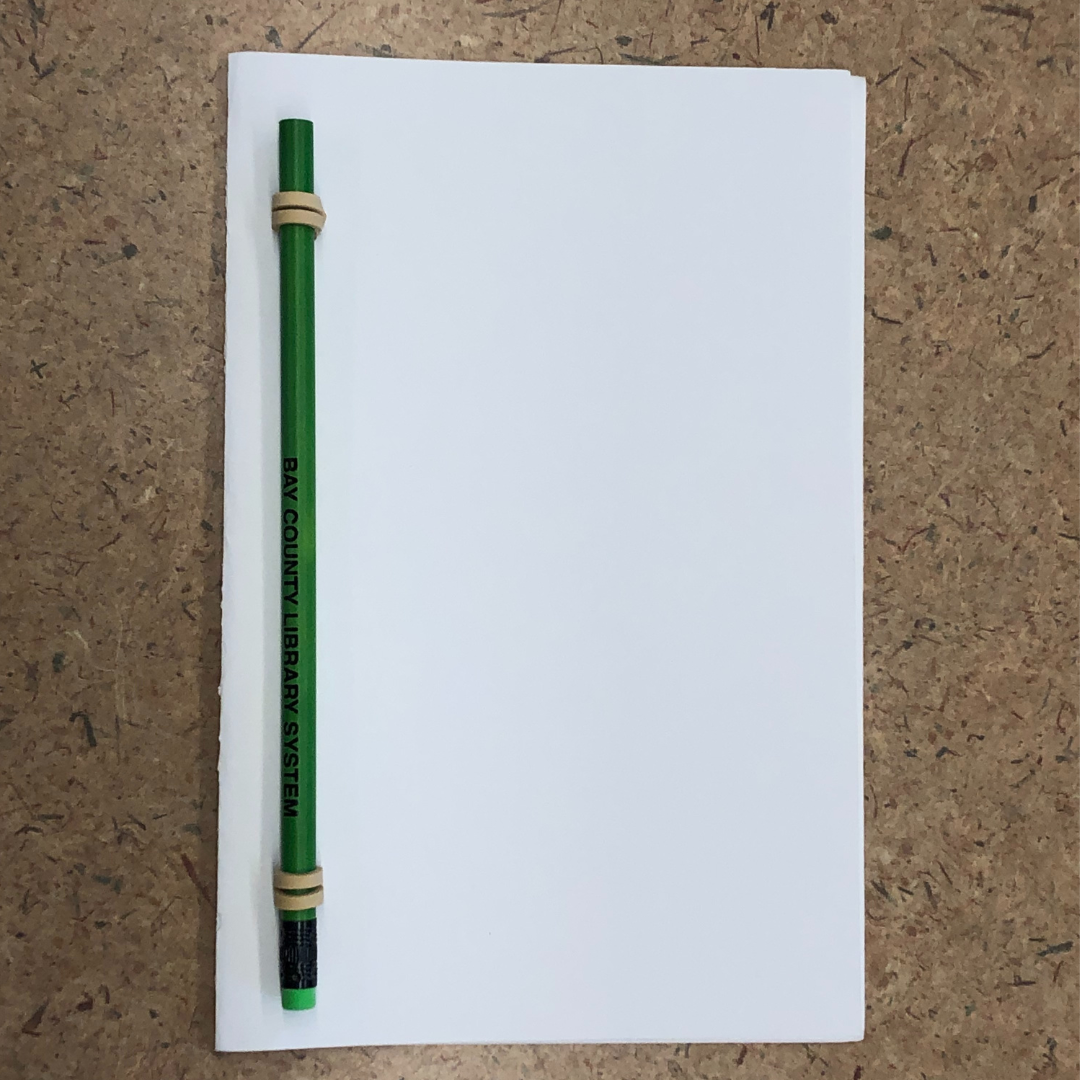 A DIY book made out of white paper, rubber bands, and a pencil