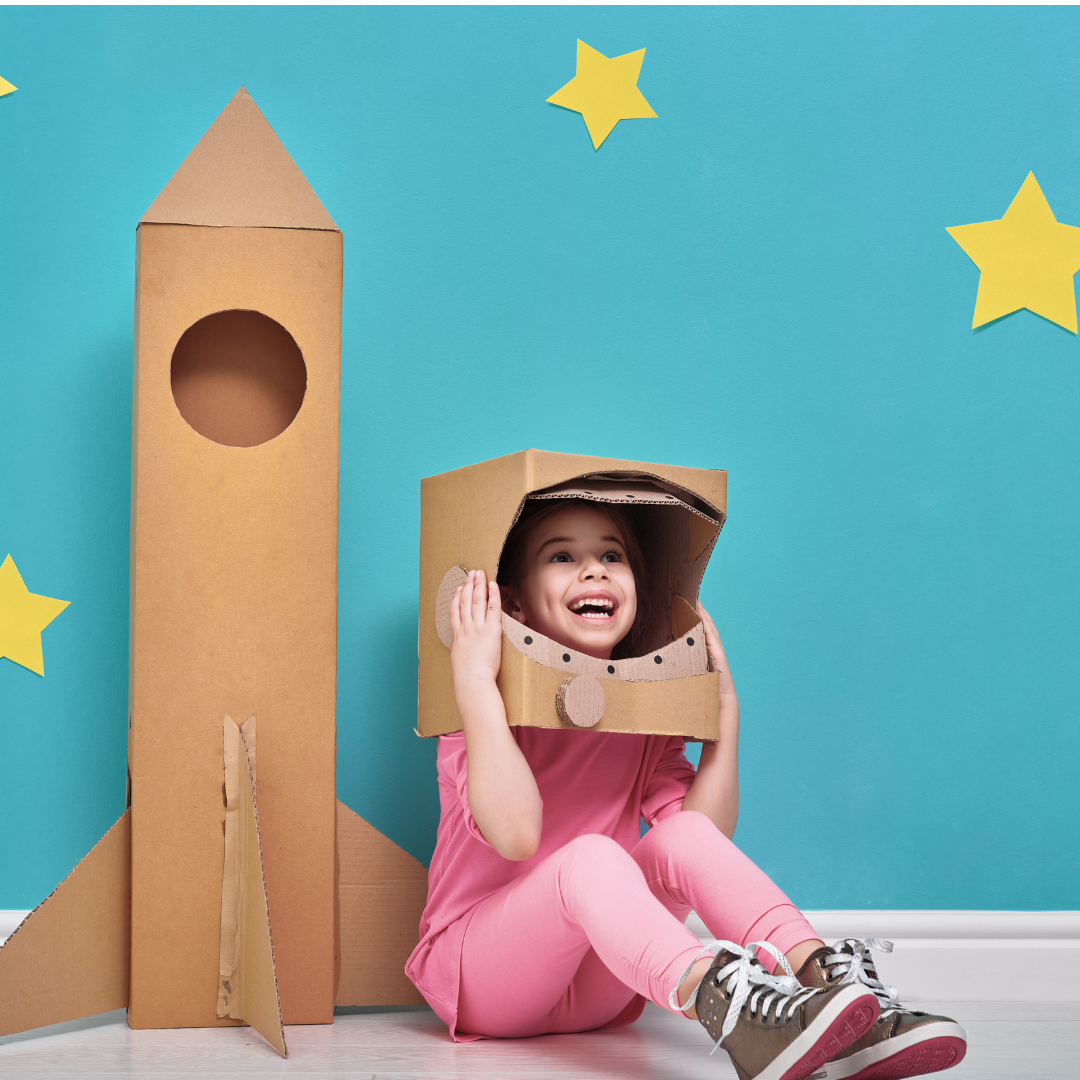 Child playing with a cardboard boxes - helmet and rocket ship 