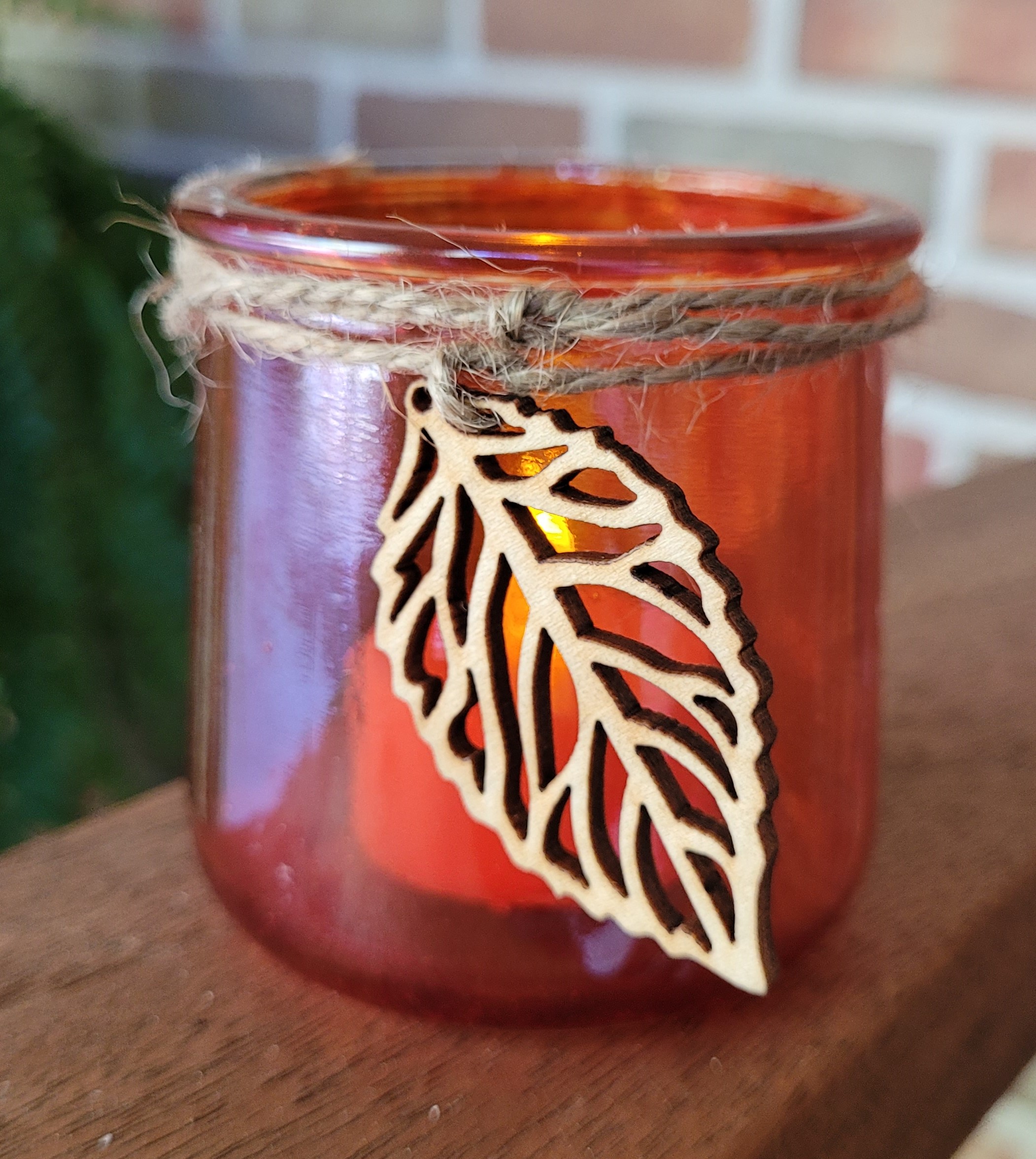 orange translucent glass votive candle holder embellished with twine and laser cut wood leaf