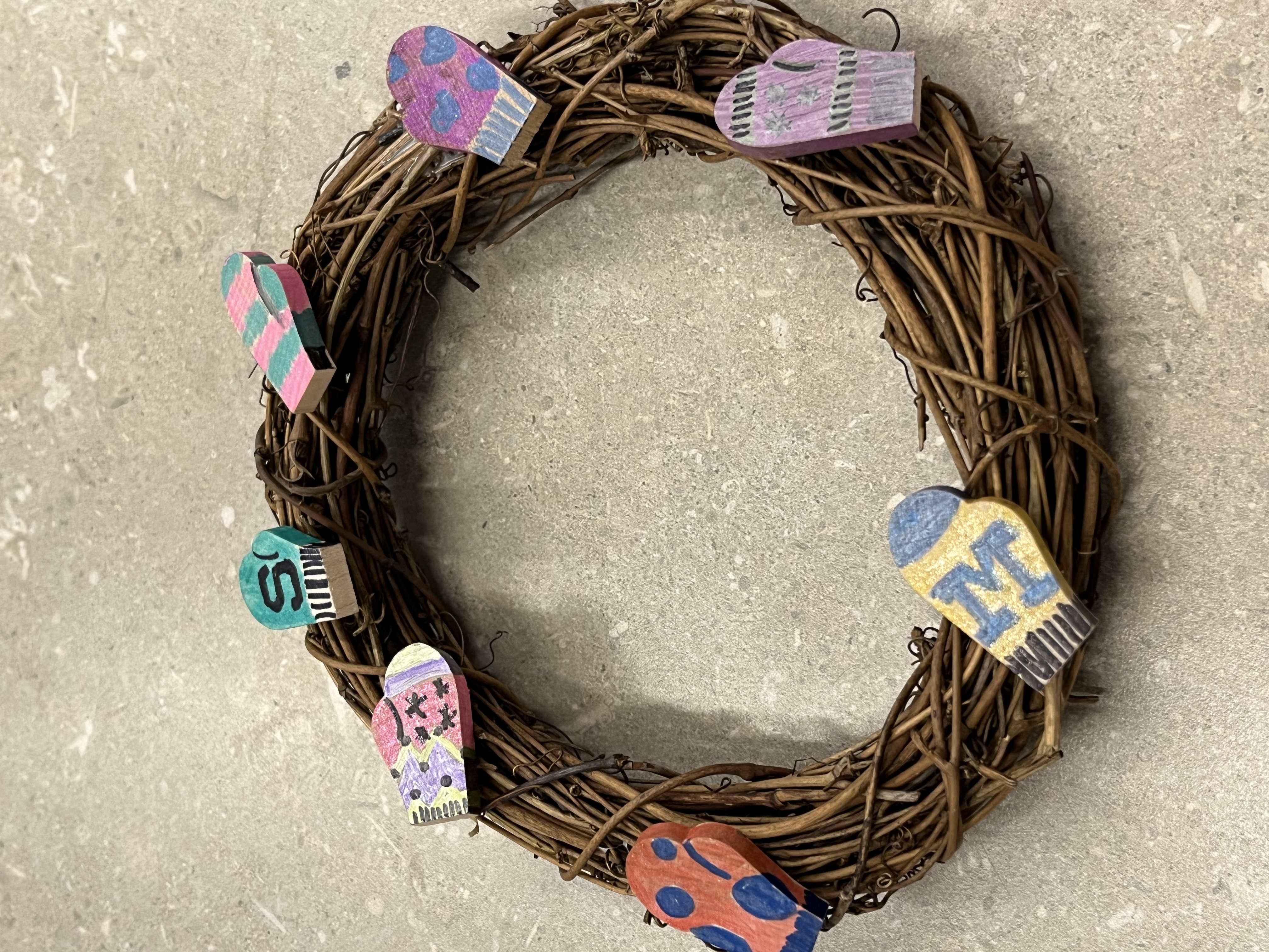A wreath decorated with wooden decorated mittens