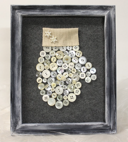 Image of mitten-shaped art made of buttons inside a frame.