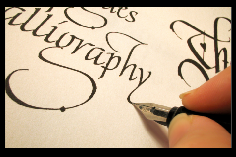 Hand with pen writing calligraphy