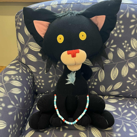 Bad Kitty stuffy wearing the necklace made out of binary coding with bead colors blue, red, and white