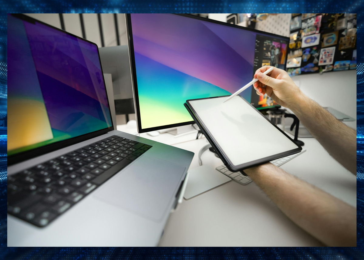 Person using tablet with laptop and computer monitor in background